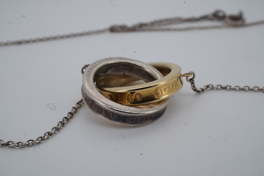 Tiffany & Co., an '1837 Interlocking Circles' pendant necklace, the pendant composed of a pair of interlocking silver and gold rings, to a silver chain, necklace length 47cm, signed T&Co, inscribed 1837, stamped 925 and